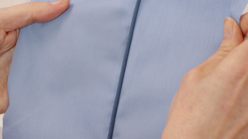 Zipper foot being used to install piping along a seam edge