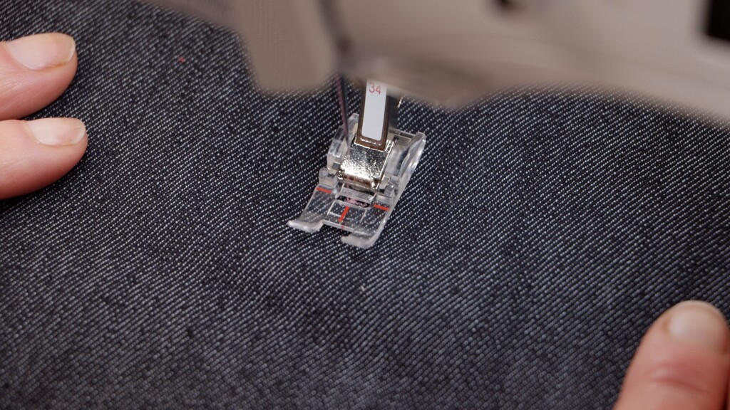 Clear view through transparent presser foot showing needle position and red alignment markings