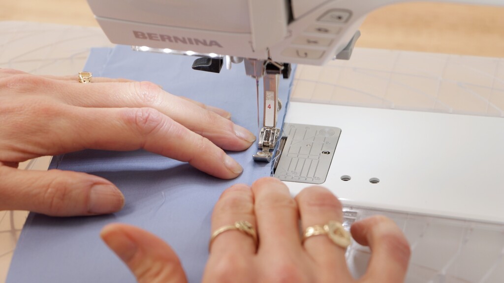 Zipper foot being used to install piping along a seam edge