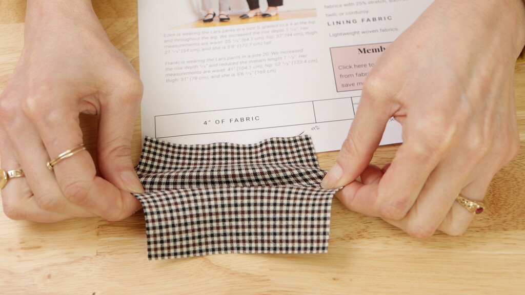 Hands performing a stretch test on knit fabric