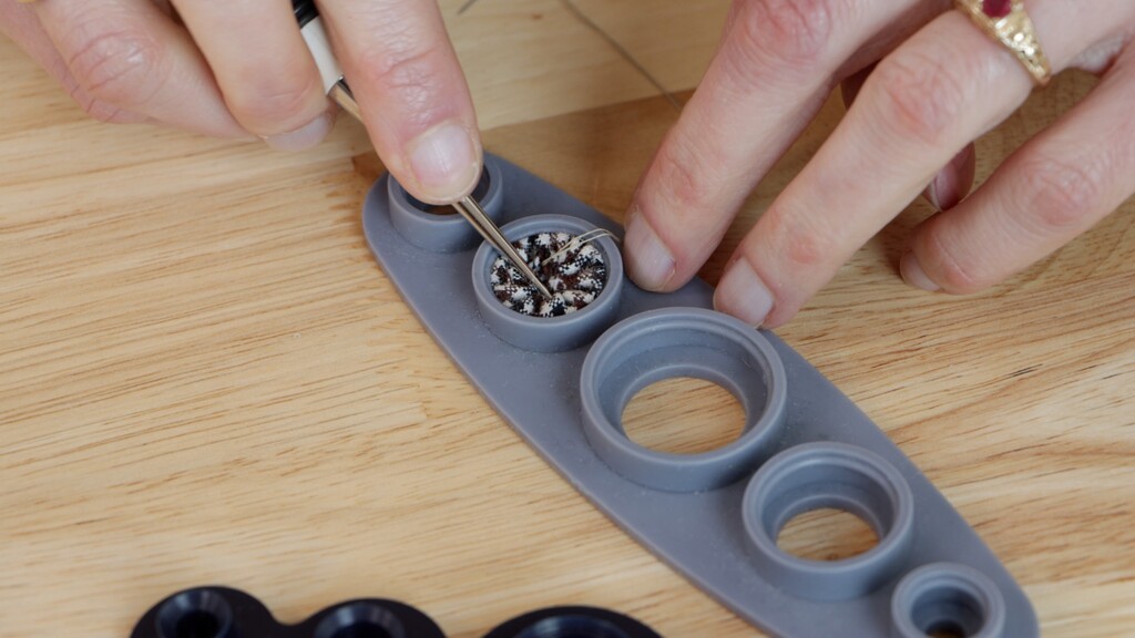 process showing fabric being gathered around button mold with the pushing tool in action