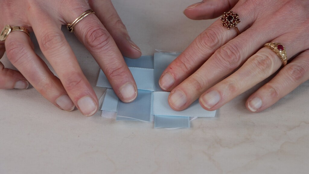 Close-up of ribbon weaving process showing the basket-weave pattern being created