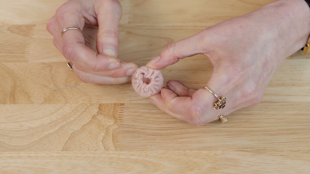 Fabric circle being gathered over plastic ring, showing the tucking technique for the raw edges