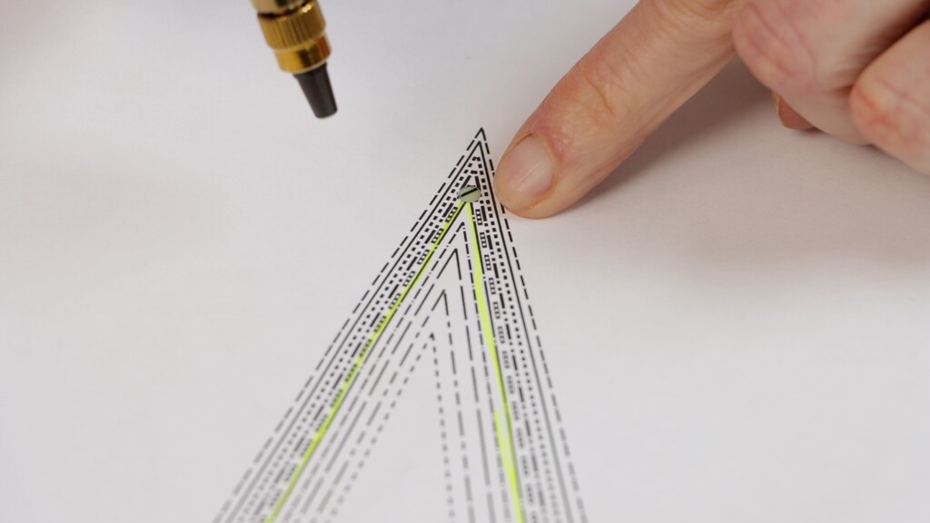 hands using a screw punch to make a precise hole at a dart tip on a paper pattern piece