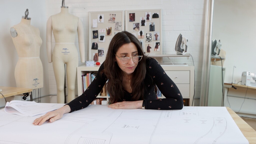 overhead view of a cutting table covered in sprawling pattern pieces with fabric scissors and measuring tape scattered around