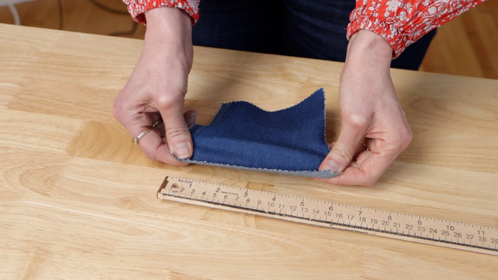 Close-up of hands stretching denim during recover test