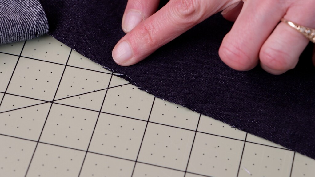 Clean-cut denim piece compared to a piece cut with a dull blade showing frayed edges