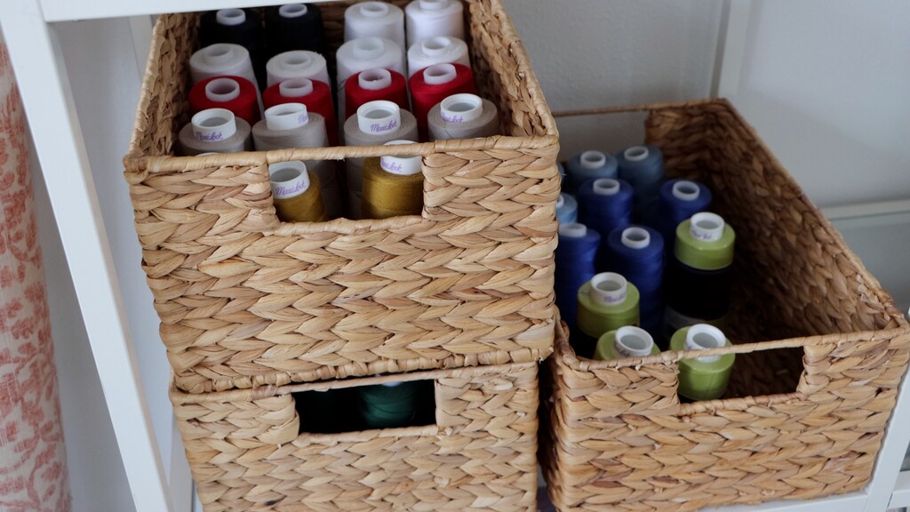 Serger thread cones organized in stackable wicker baskets on shelf