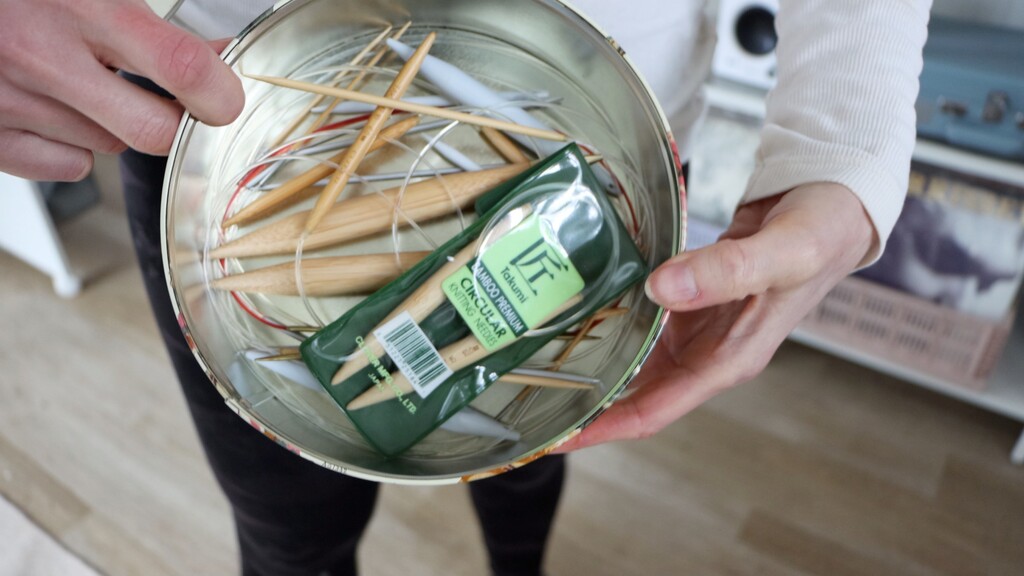 Decorative cookie tin opened to show circular knitting needles stored inside