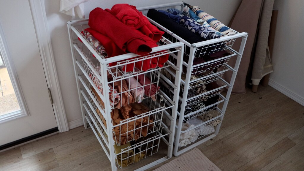 Rack with slide-out baskets filled with rolled fabric pieces organized by color