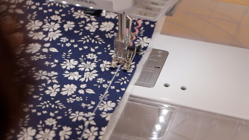 Close-up of the first scallop pass being stitched on the machine, showing the scallop stitch forming along the guideline