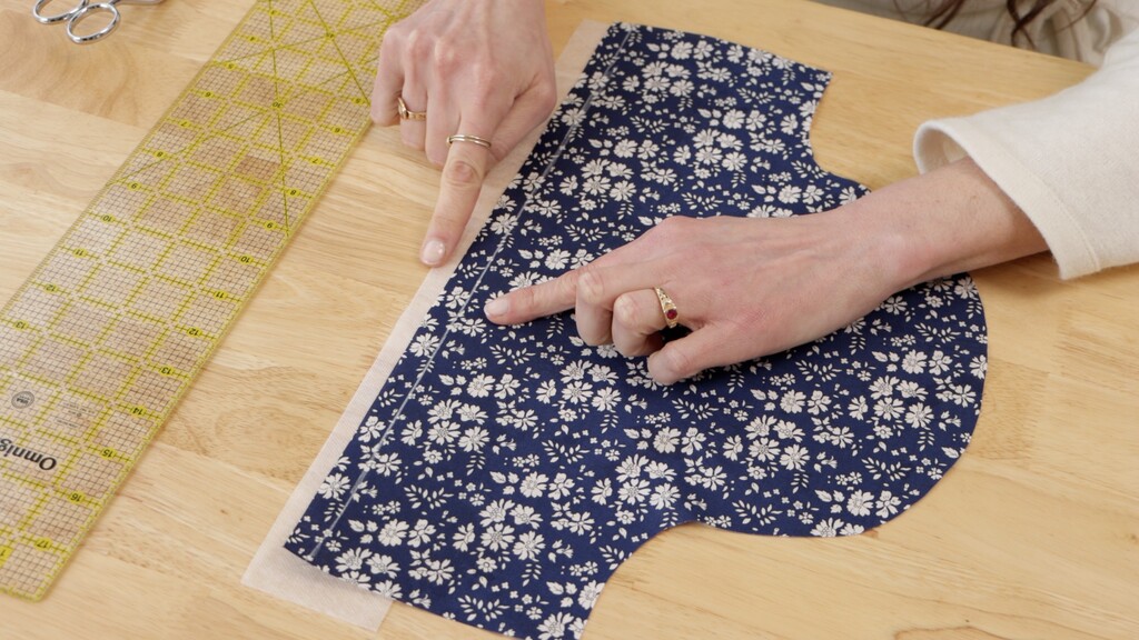 Fabric edge with marked stitching guideline and stabilizer pinned in place beneath it