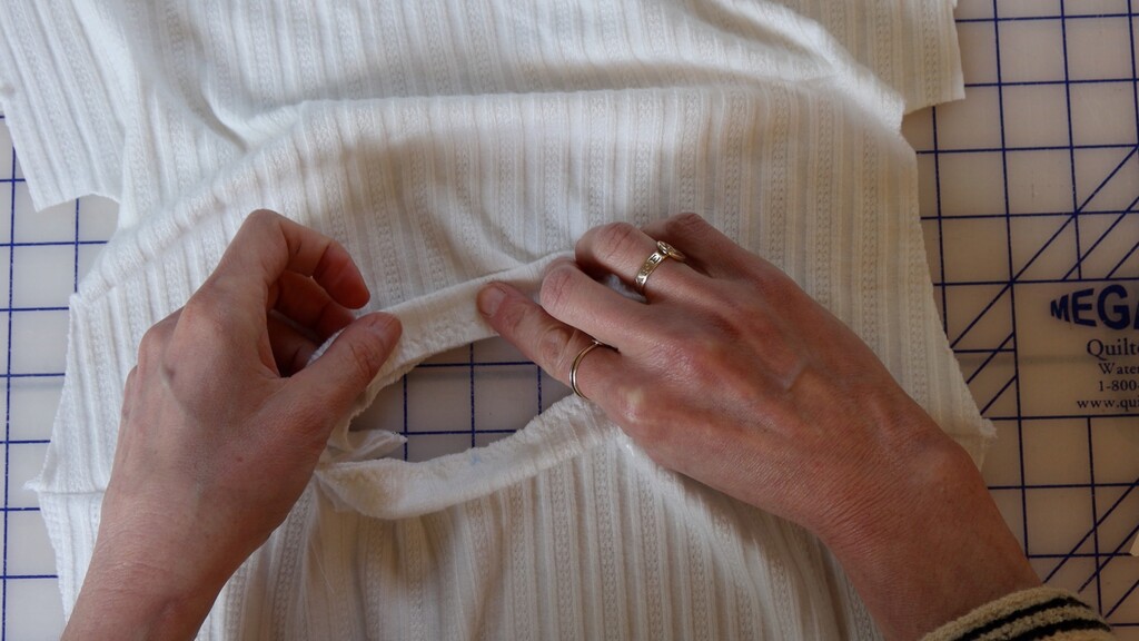 Neckband being applied to the tee neckline with Wonder Tape, showing the band stretched and adhered in place