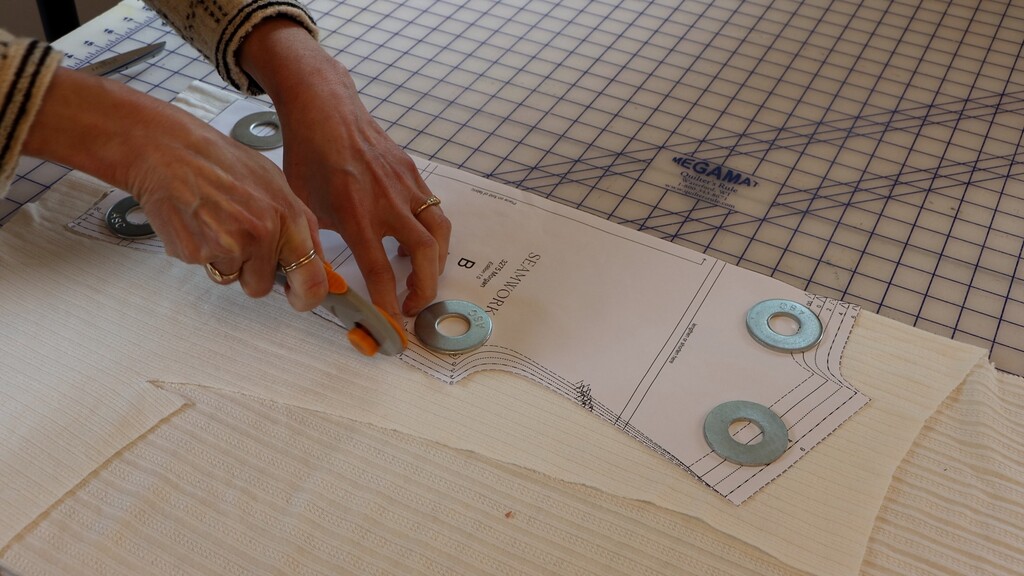 Cutting fabric with a rotary cutter, pattern pieces laid out on knit fabric