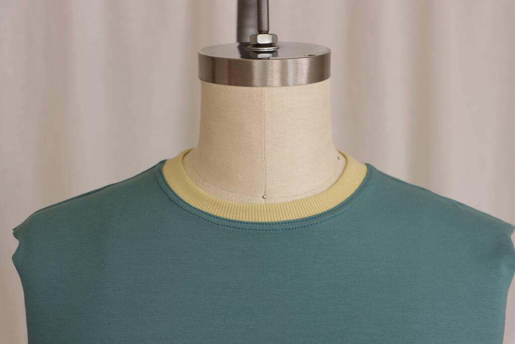 Close-up of twin needle topstitching on a neckband, showing the two parallel lines of stitching on the right side of the fabric