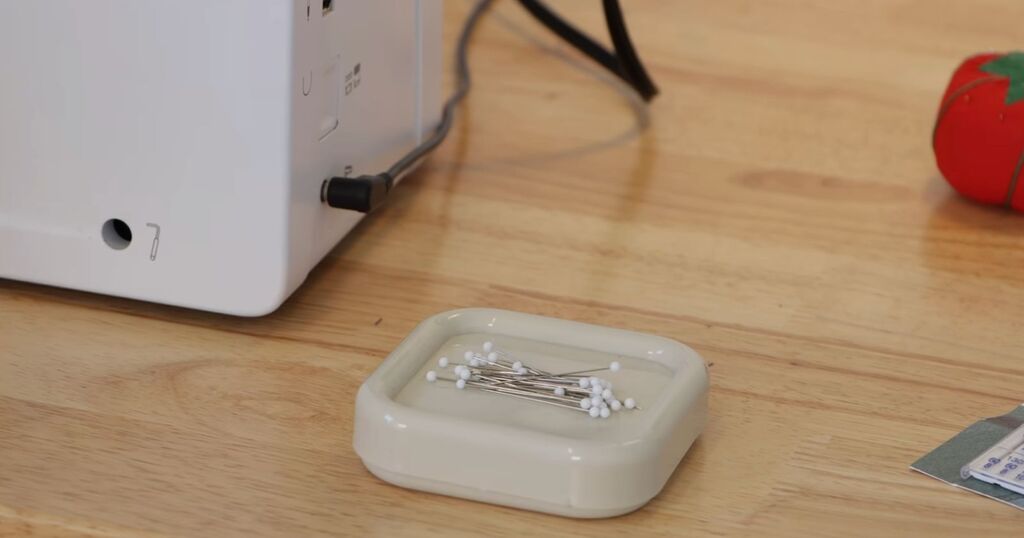 A magnetic pincushion with pins scattered across the top, held in place by the magnet