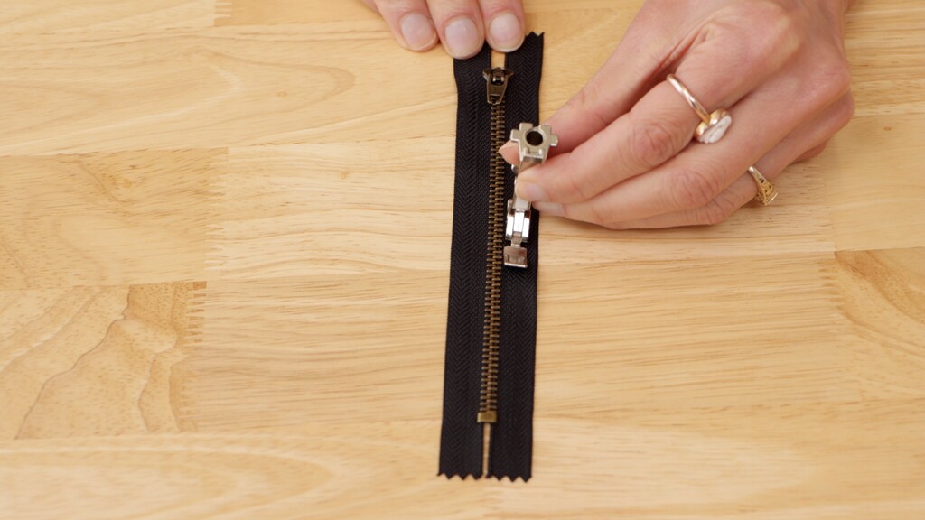 Close-up of a zipper foot stitching alongside a fly zipper on deni