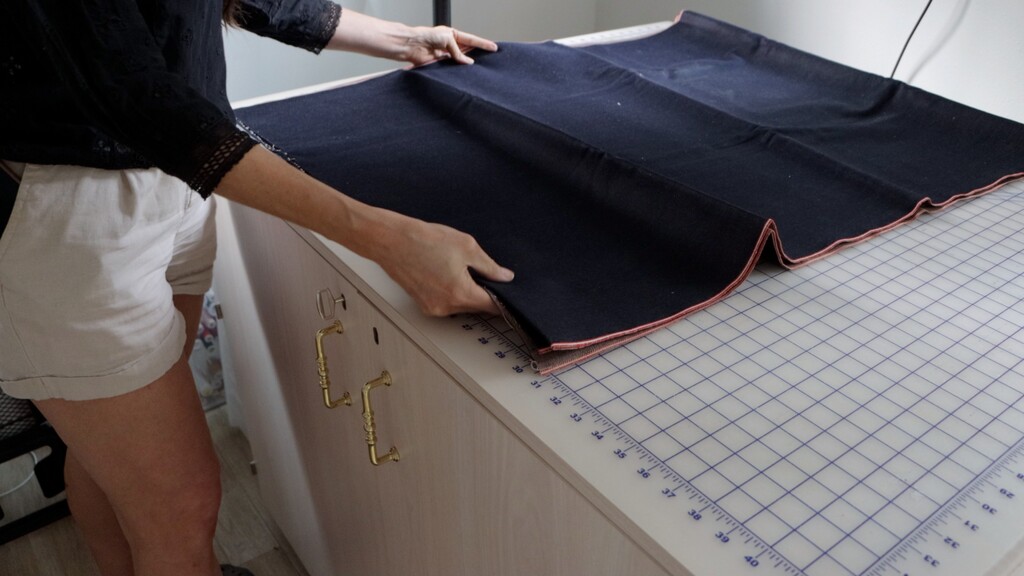 Iron and ironing board set up in a sewing space, with a piece of fabric being pressed before cutting